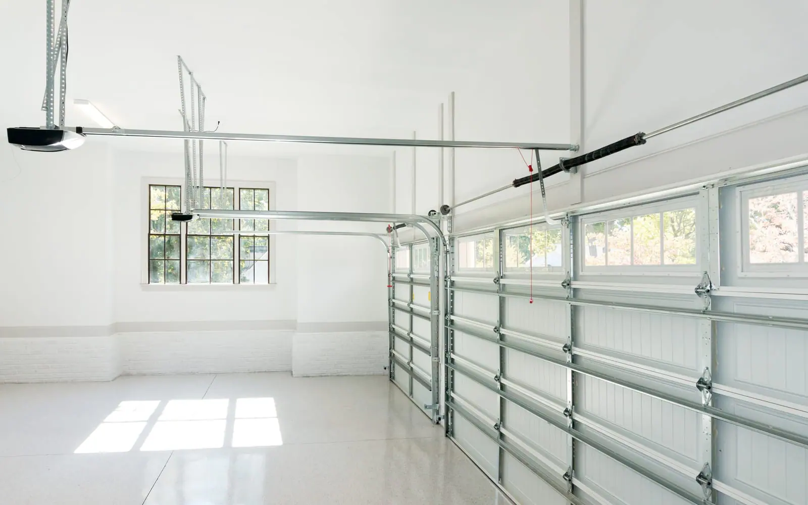 Inside a bright garage: door tracks, rollers and the opener rail