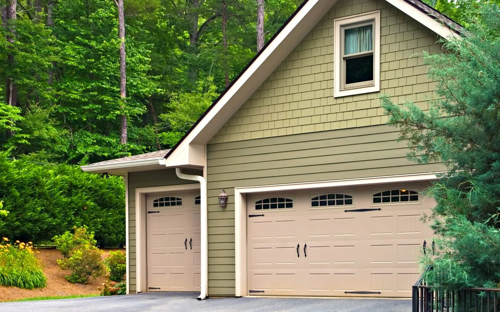 Green craftsman-style house with tan carriage-style garage doors
