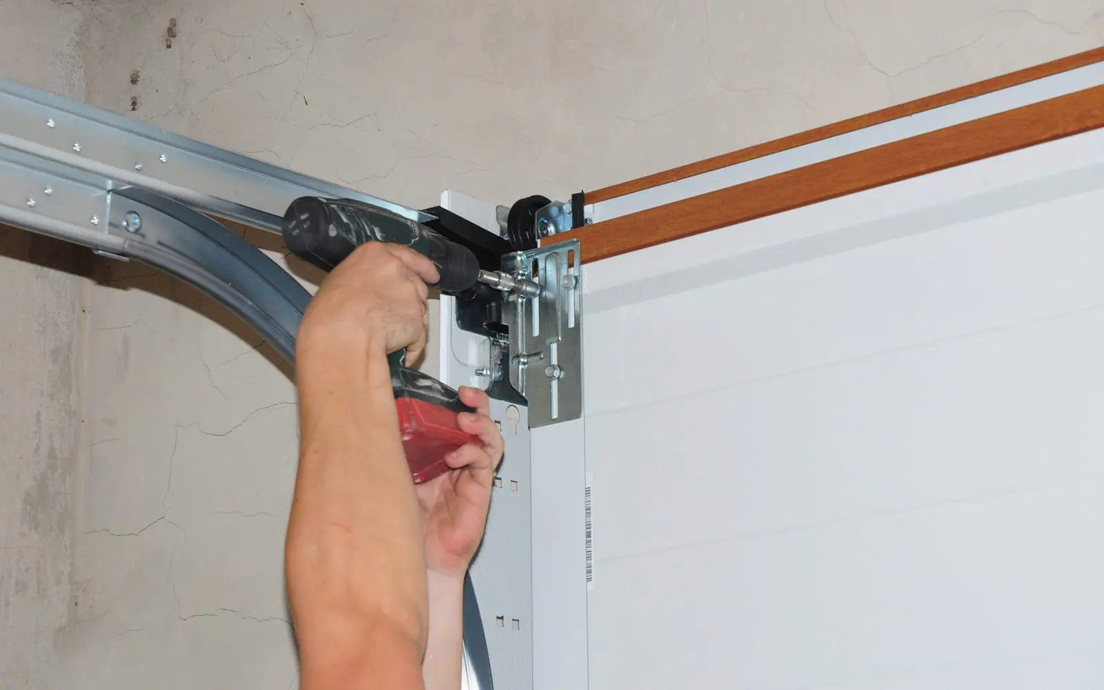 Hand tightening a bracket where a garage door meets its track