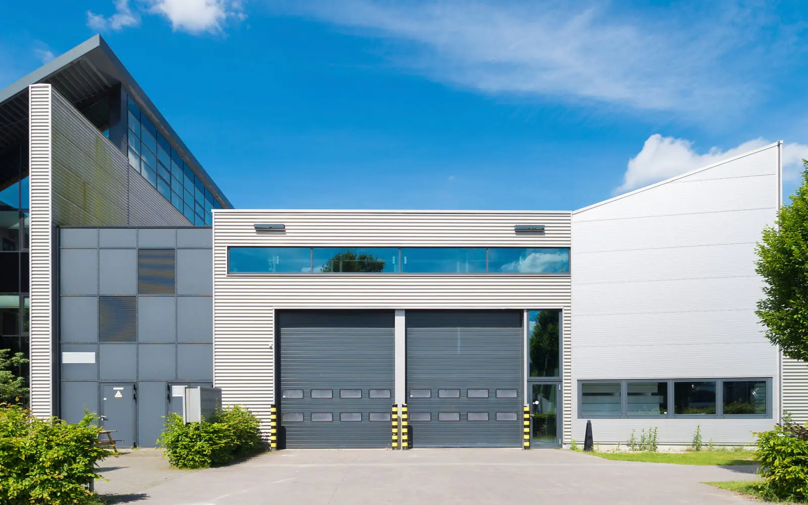 Modern commercial building with two dark gray overhead sectional doors