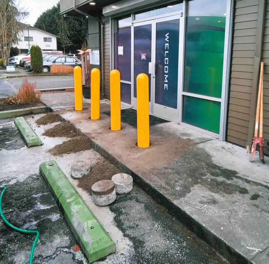 Four yellow bollards in front of a storefront entrance