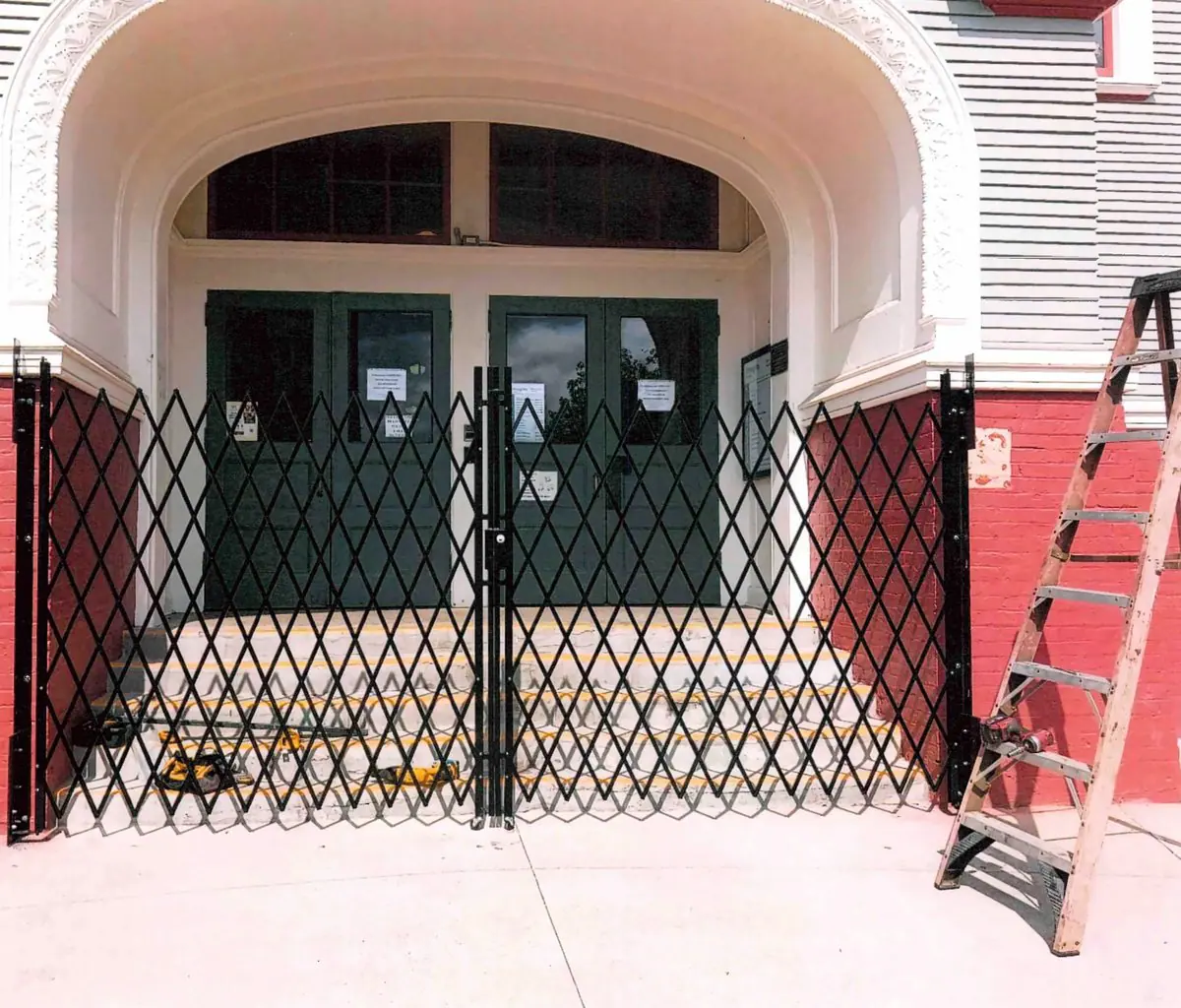 Pair of folding gates across an arched entrance, with a ladder alongside