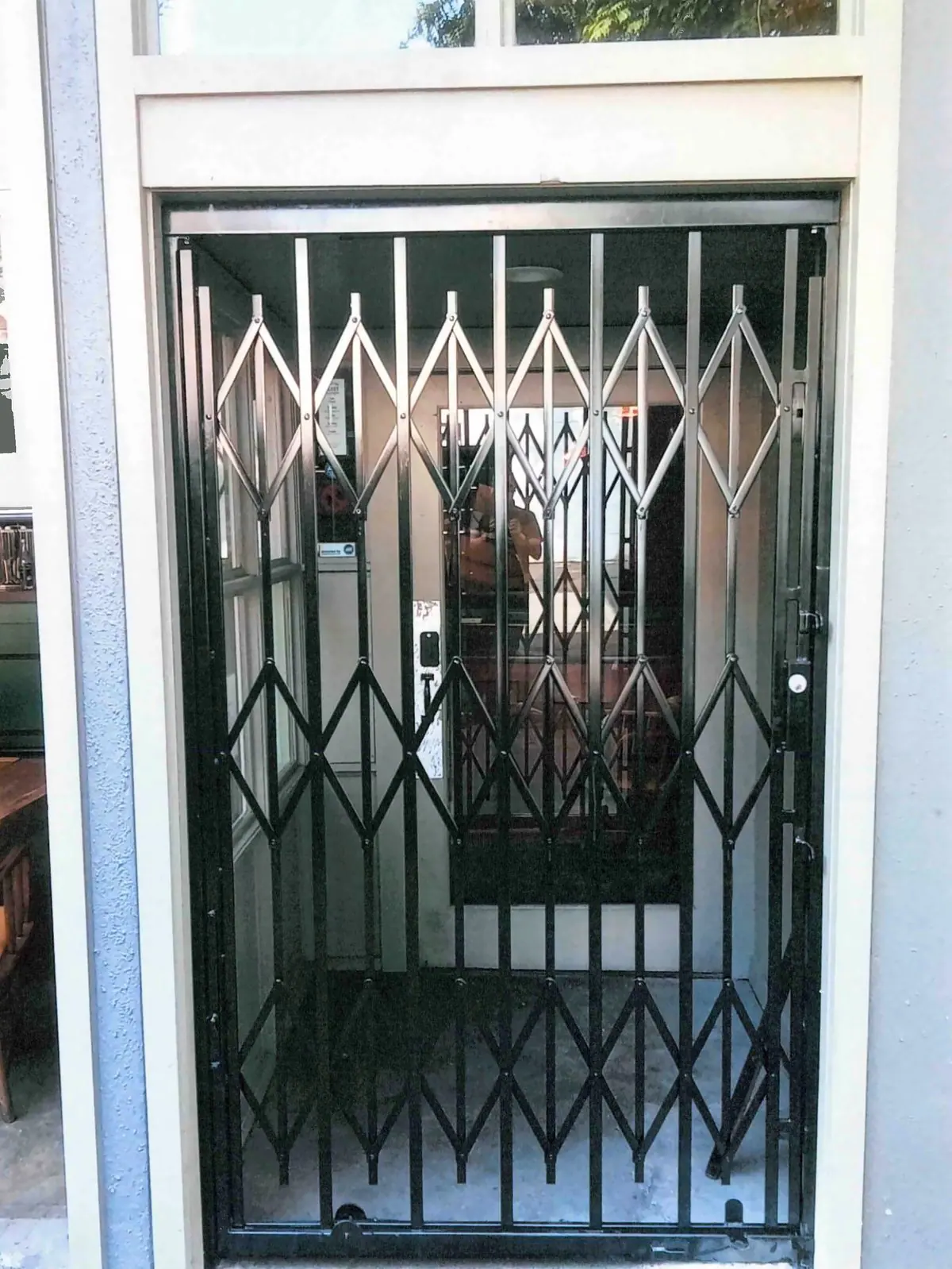 Folding security gate closed across a recessed storefront entry