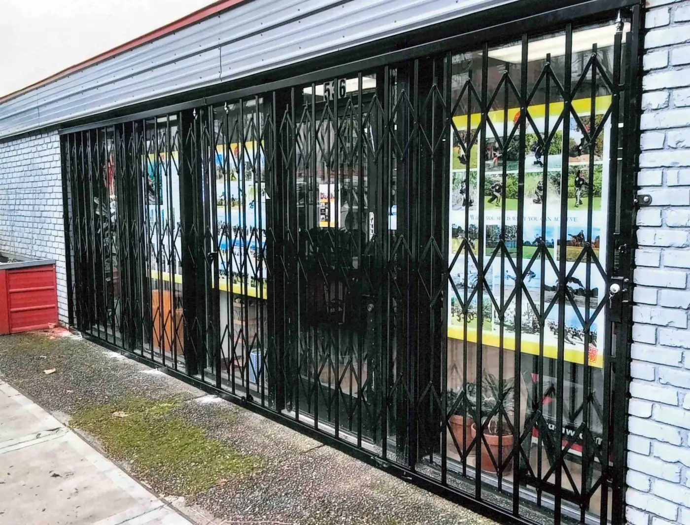 Folding security gate closed across a row of storefront windows