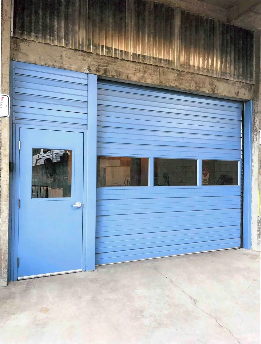 Blue rolling steel door with windows and a matching steel entry door