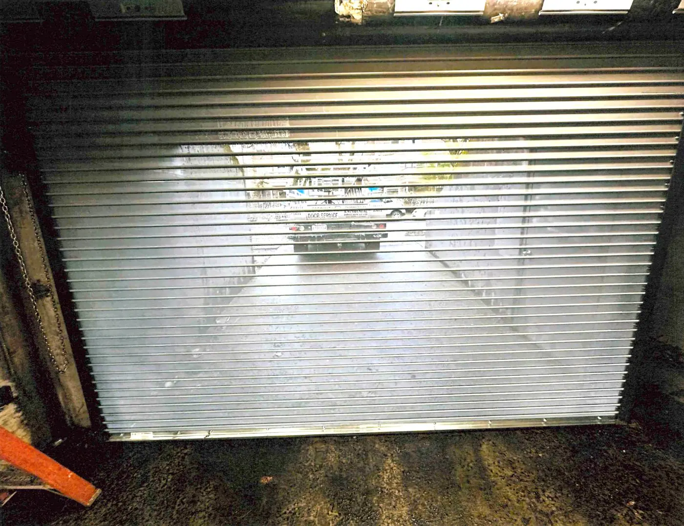 Rolling steel door with a Specialty Door Service truck showing in the slats