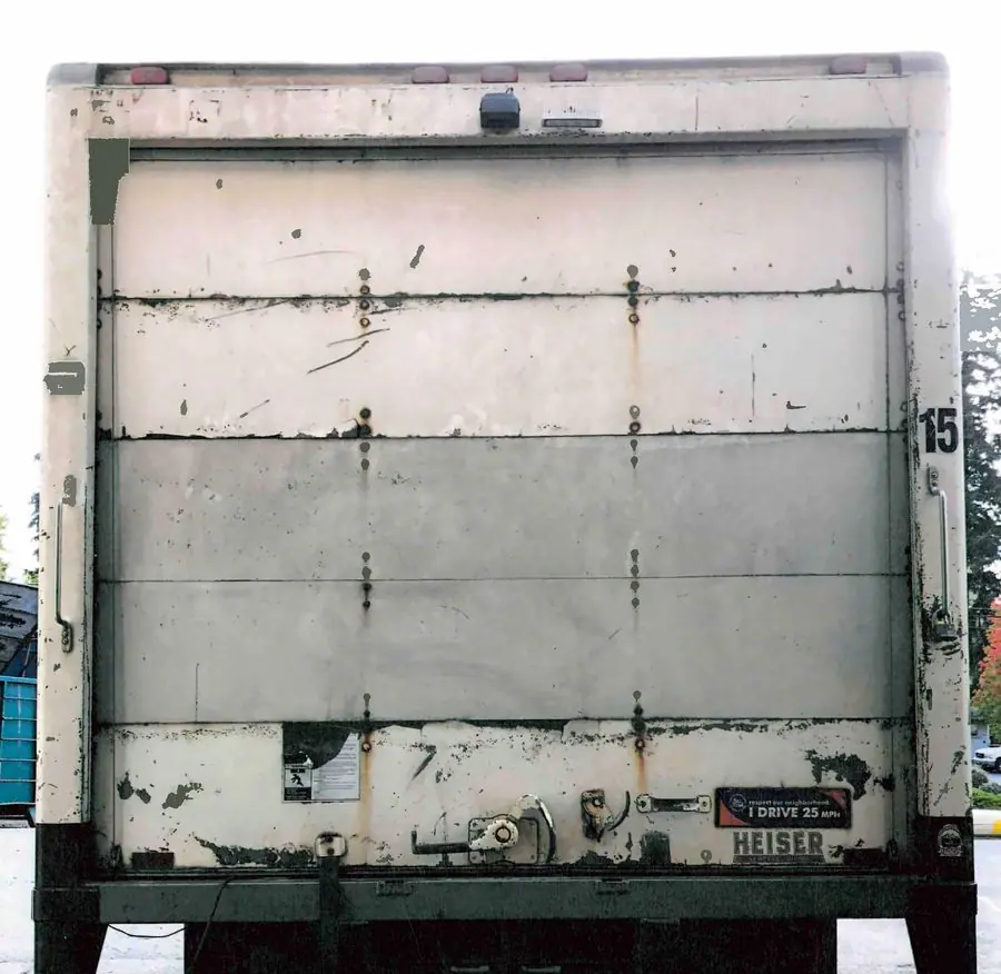 Back of a box truck with a worn, patched roll-up door