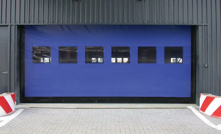 Blue high-speed fabric door with a row of windows on a dark metal building