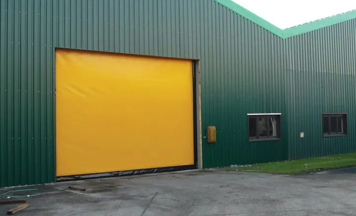 Yellow high-speed fabric door on a green metal building