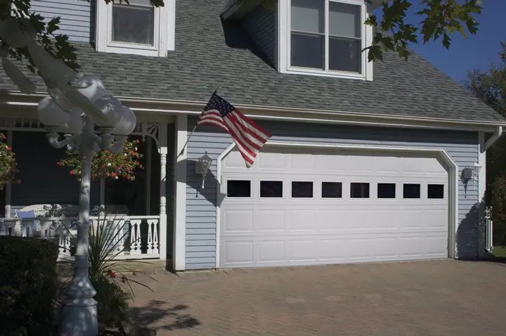 Gray two-story home with a white garage door with a row of windows