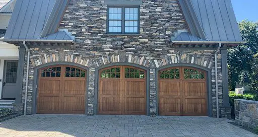 Stone home with three arched wood carriage house garage doors