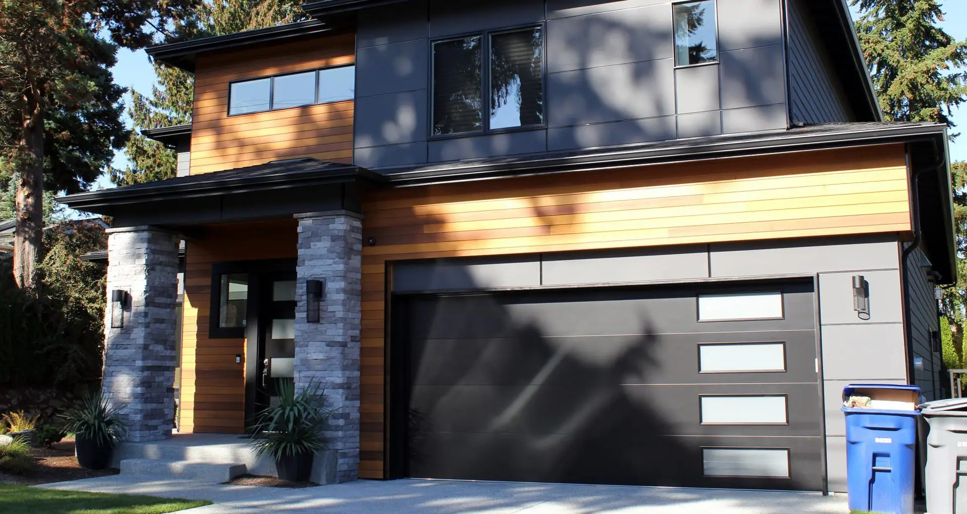 Modern wood and stone home with a dark garage door
