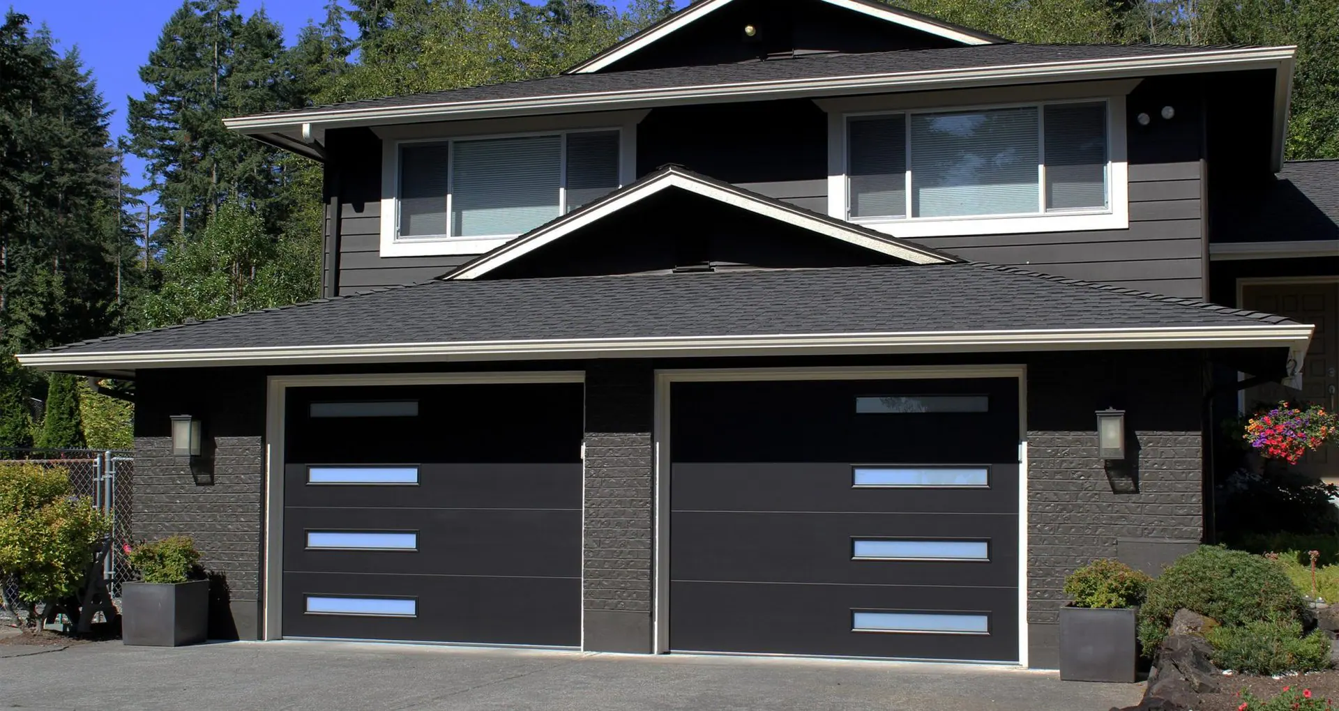 Dark modern home with two black garage doors with offset windows