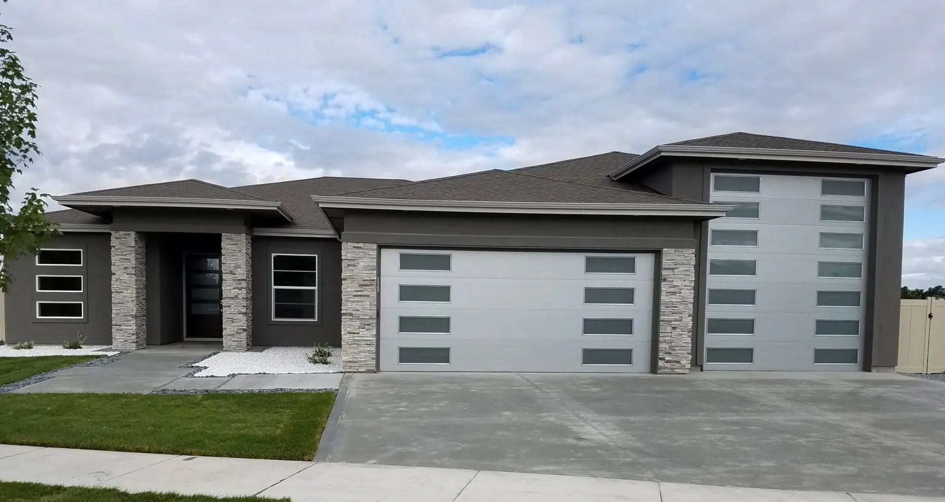 Gray single-story home with a silver garage door with side windows